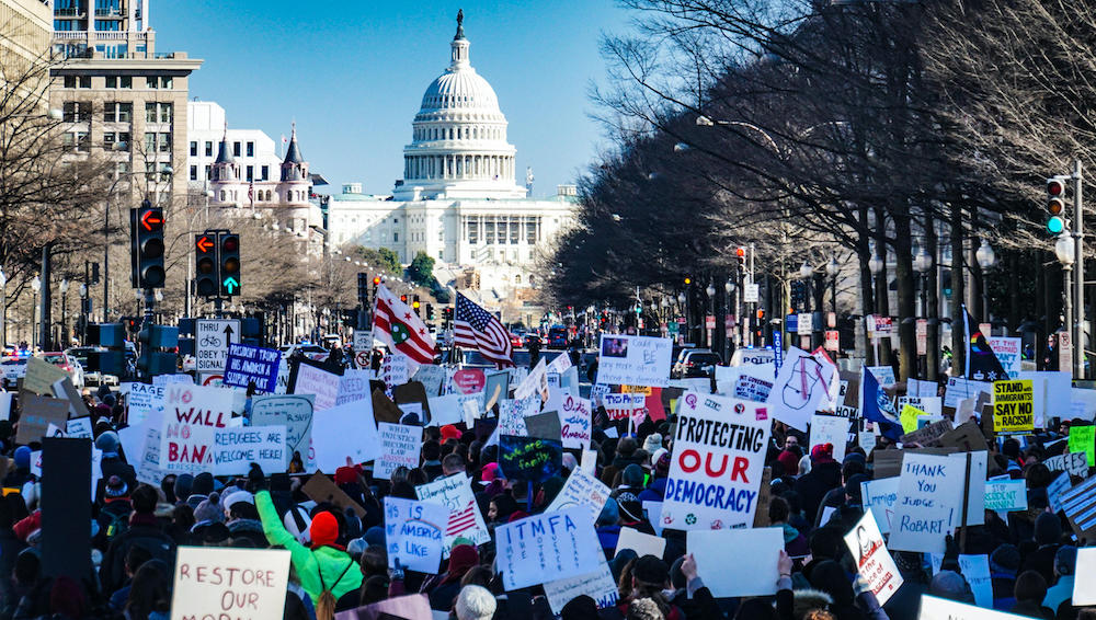 Protestors outside the Whitehouse holding up banners with slogans including "Protecting our Democracy"