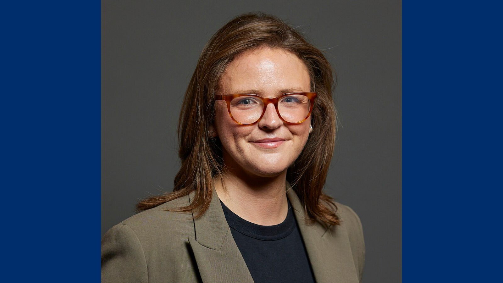 Portrait picture of Lauren Edwards MP with brown hair, a grey jacket and glasses.